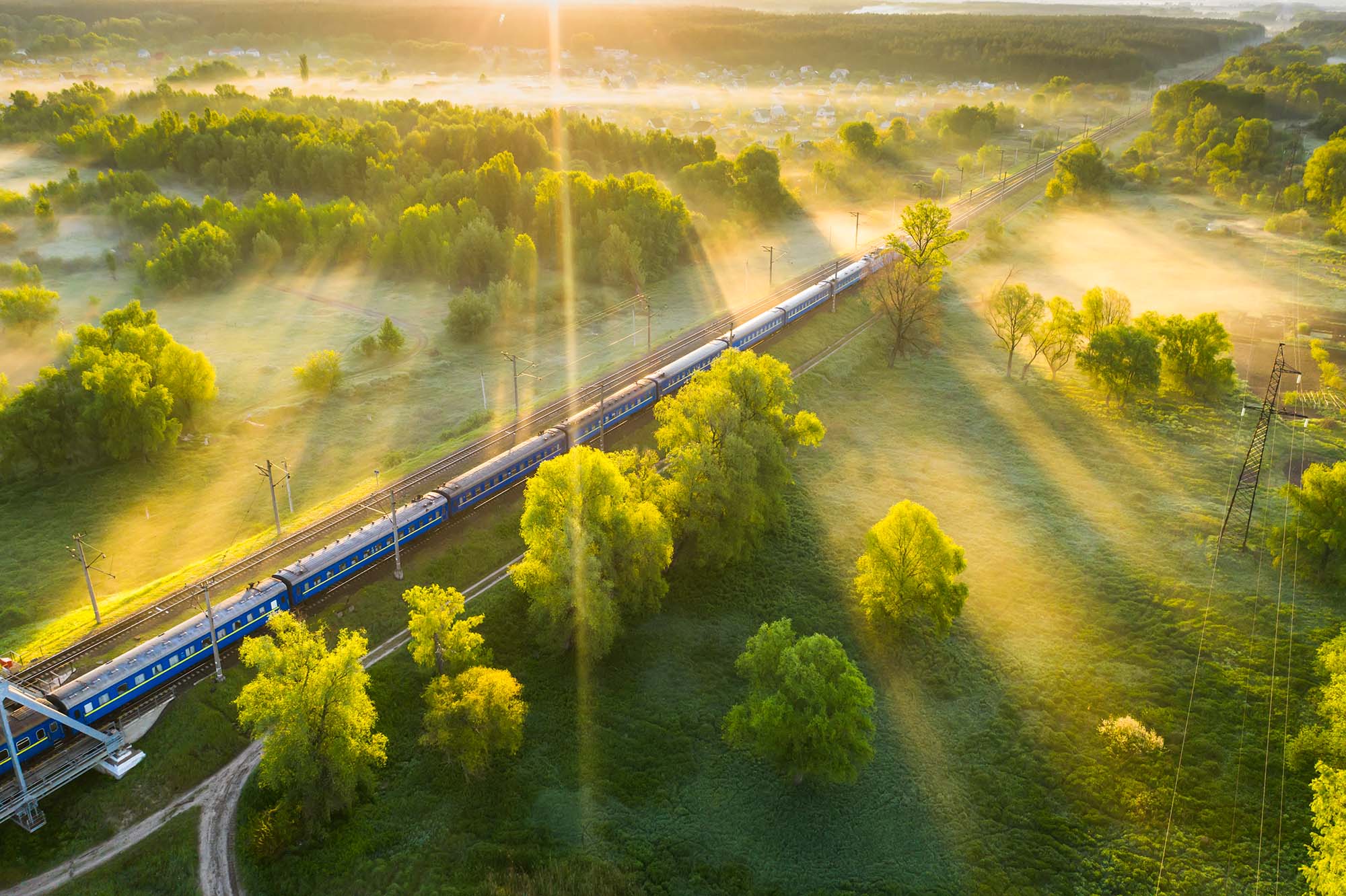 Tåg passerar ett grönt landskap i soluppgången