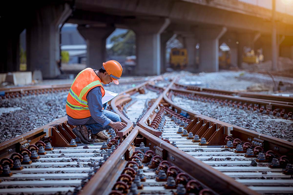 A man in an orange safety vest inspects the railway tracks