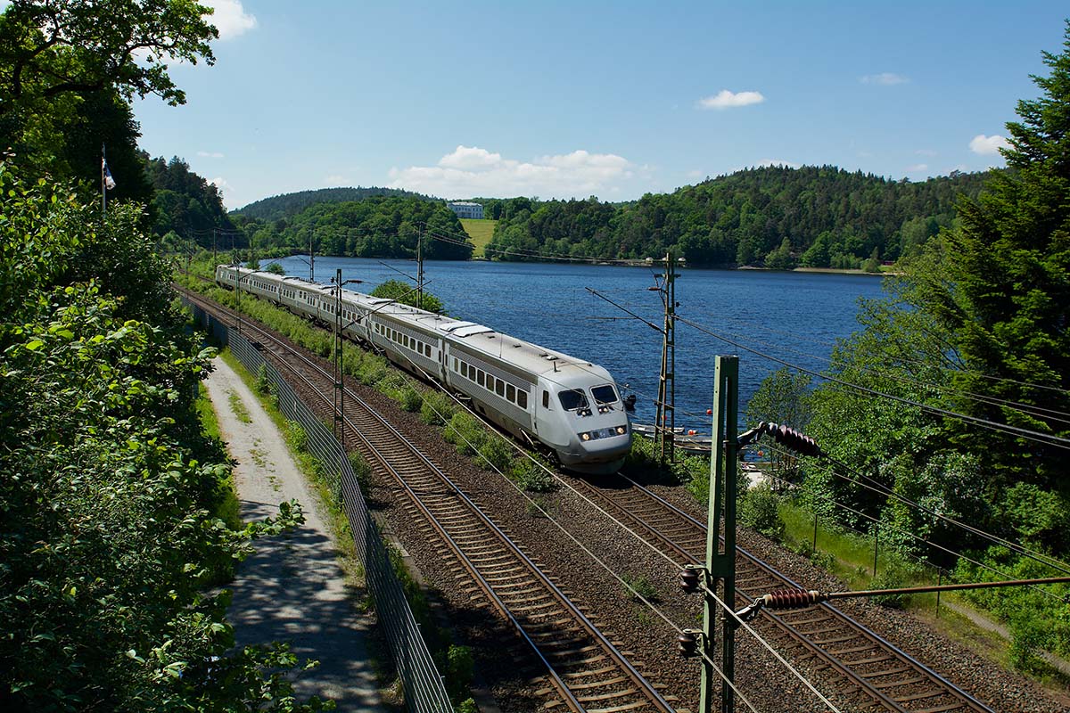 An X2000 train in a beautiful green landscape